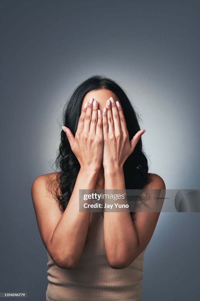 Shot of a young woman posing with her hands over her face