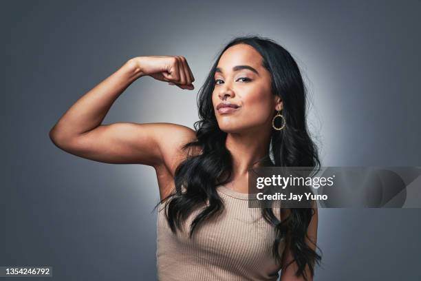 studio shot of a beautiful young woman flexing while standing against a grey background - boston premiere of stronger stockfoto's en -beelden