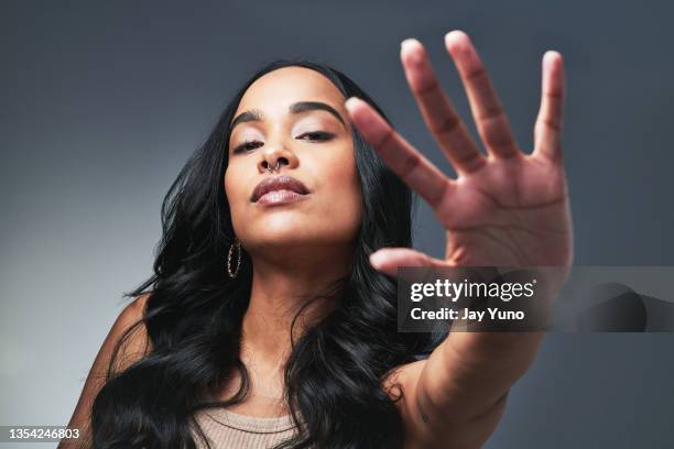 studio shot of a beautiful young woman showing the stop gesture - bold attitude stock pictures, royalty-free photos & images