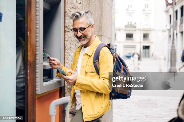 mature tourist taking the money on the atm - returning money stock pictures, royalty-free photos & images