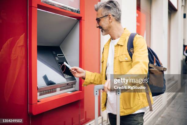 mature man on a journey taking the money at the atm - atm stock pictures, royalty-free photos & images