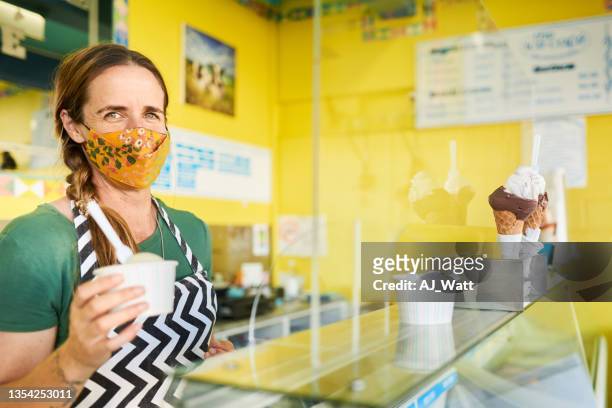 lächelnde unternehmerin steht an der theke ihres eisstandes - ice cream counter stock-fotos und bilder