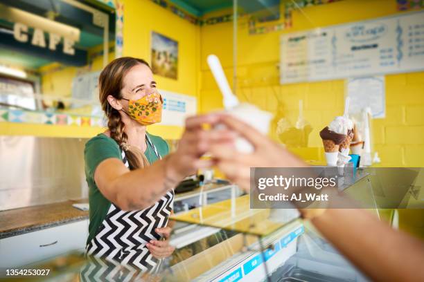 smiling entrepreneur helping a customer at her ice cream stand - owner stand stockfoto's en -beelden
