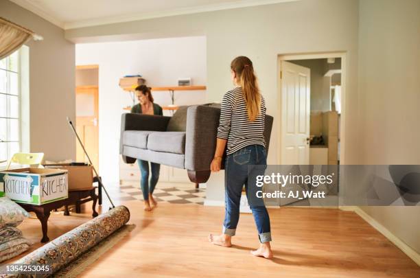 female friends carrying a sofa out of a house on moving day - first apartment stock pictures, royalty-free photos & images