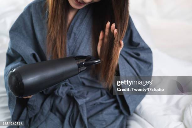 young asian female dry hair with blower - hair dryer stock photos et images de collection