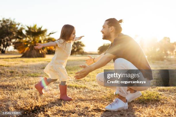 carefree young father and daughter hugging in spring day. - dad daughter stock pictures, royalty-free photos & images