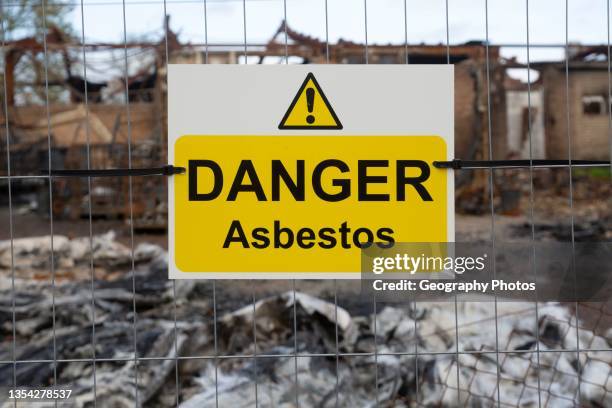 Industrial building destroyed by fire, Hatcher Components Ltd, Parham airfield, Suffolk, England, UK - Danger Asbestos sign.