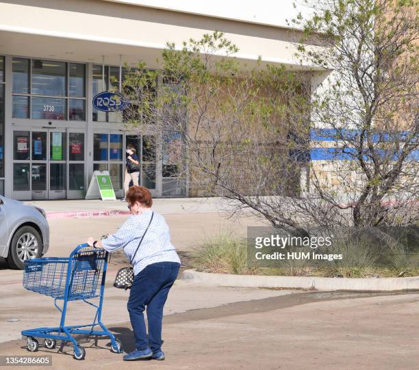 Woman pushes a shopping cart toward a Ross Dress for Less store.