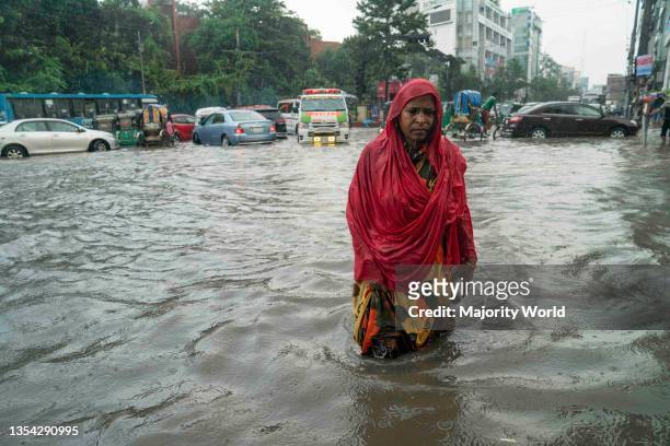 Woman walks through rain water on the streets during the monsoon rain. Couple of hours of rain create waterlogging on the streets as the sewerage and...