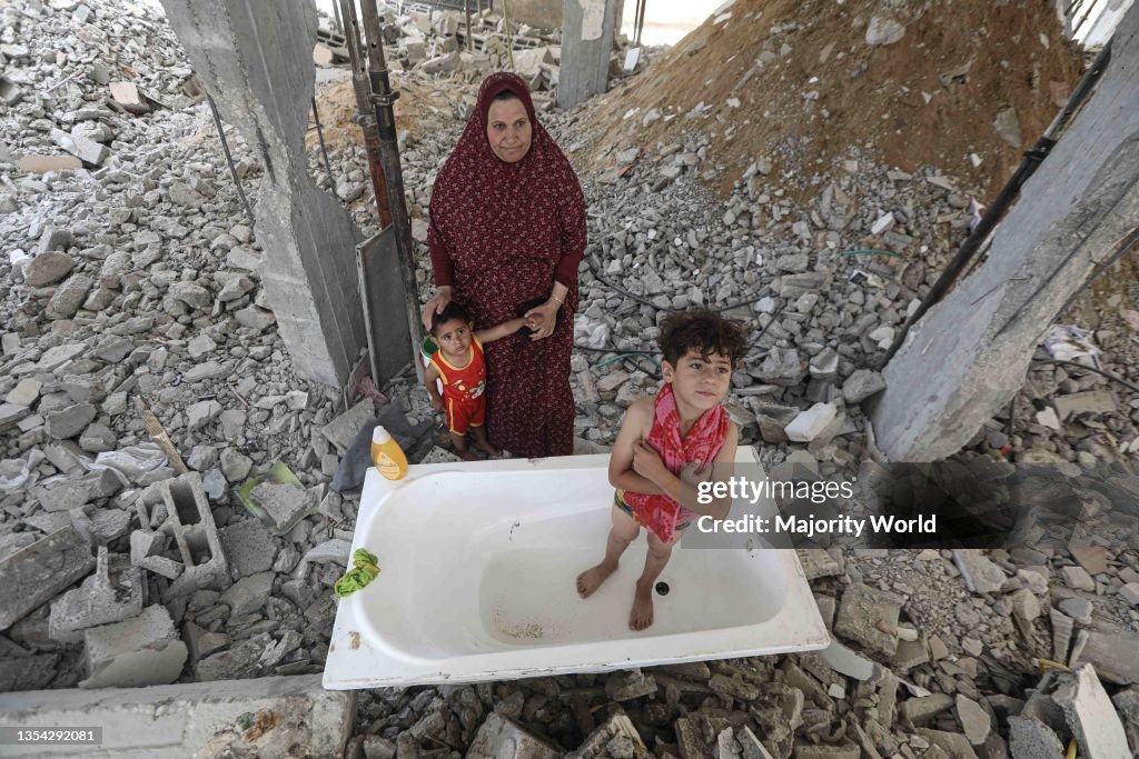A woman washes her children inside a destroyed house in Gaza City.