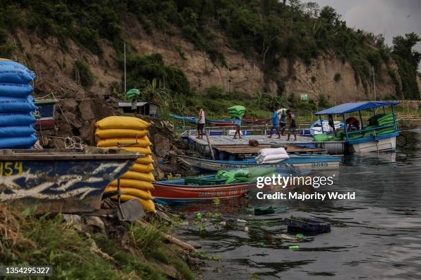 Fishermen load sacks of fish feeds on to small boats as the Taal volcano releases smoke and ash in Agoncillo town, Batangas province south of Manila....