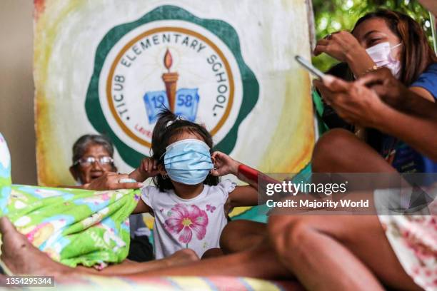 Child plays with her protective mask as residents stay inside a school turned into a temporary evacuation center as the Taal volcano releases smoke...