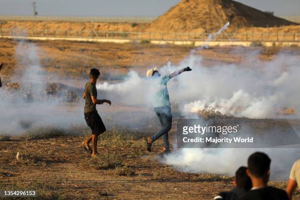Gaza Strip. 26th August 2021. Palestinian demonstrators run from tear gas fired by Israeli security forces during a protest along the border fence,...
