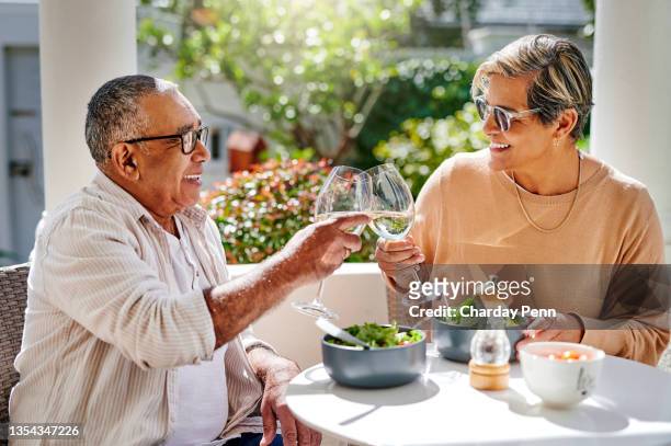shot of a senior couple toasting while having lunch outside - paleo diet stock pictures, royalty-free photos & images