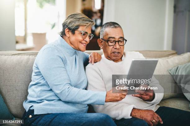 shot of a senior couple using a digital tablet at home - een tablet gebruiken stockfoto's en -beelden