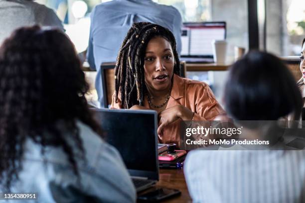 young professional women collaborating in coffeeshop - locs hairstyle stock pictures, royalty-free photos & images