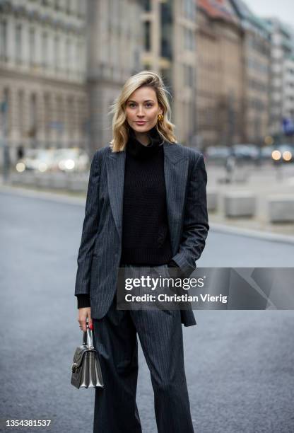 Mandy Bork is seen wearing striped suit Brunello Cucinelli, silver Bulgari bag, yellow Amina Muaddi heels, black NAKD turtleneck on November 19, 2021...