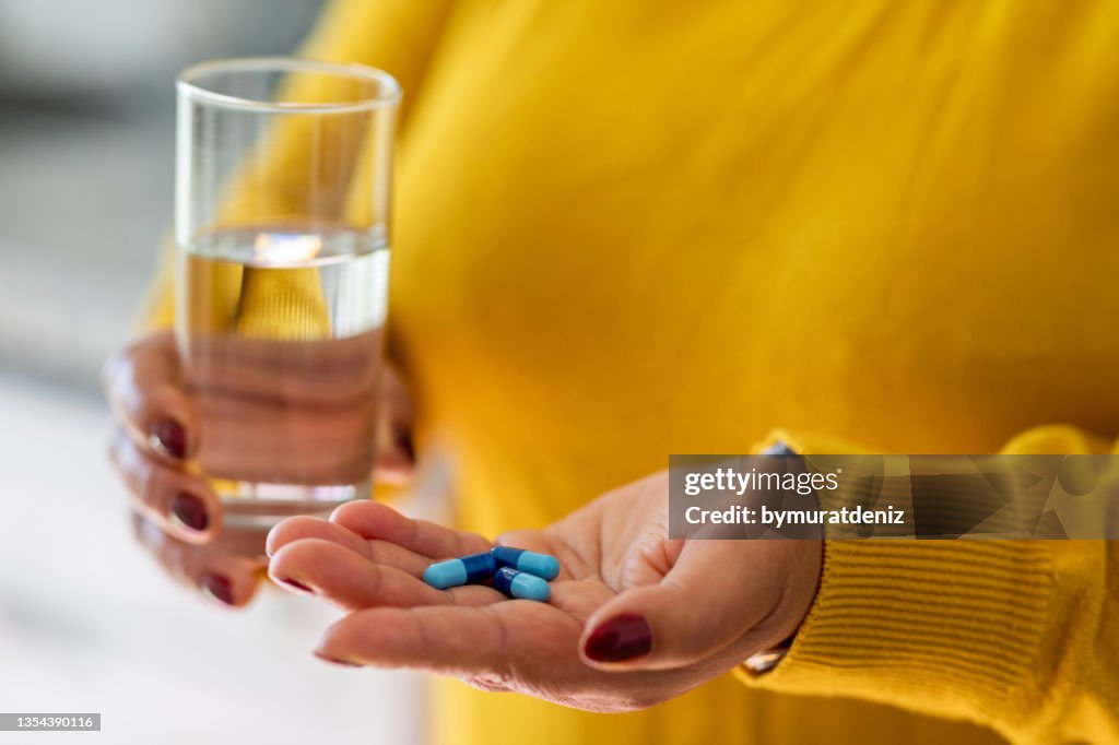 Woman takes medicines with glass of water