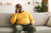 Senior African American Man Talking On Cellphone Sitting At Home