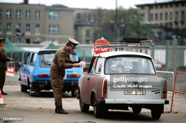 An East German policeman monitors traffic returning to East Berlin through the newly created opening in the Berlin Wall at Potsdamer Platz.