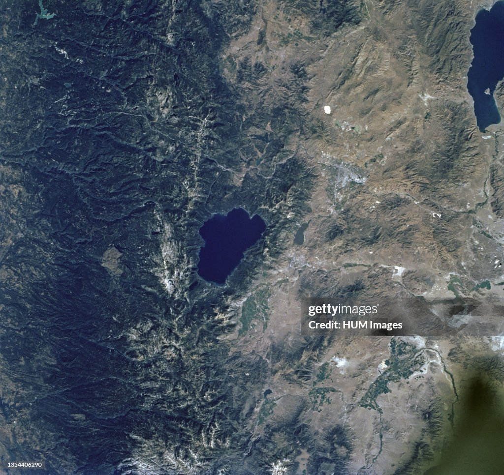 The dark green forests of the Sierra Nevada Mts. occupy the left side of the picture. Reno lies between Lake Tahoe (center) and Pyramid Lake (top right) ca. 1997