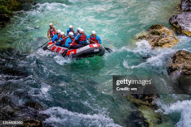 people riding down water in gorge in raft, crystal clear turquoise water making waves around stones - stroomversnelling stockfoto's en -beelden