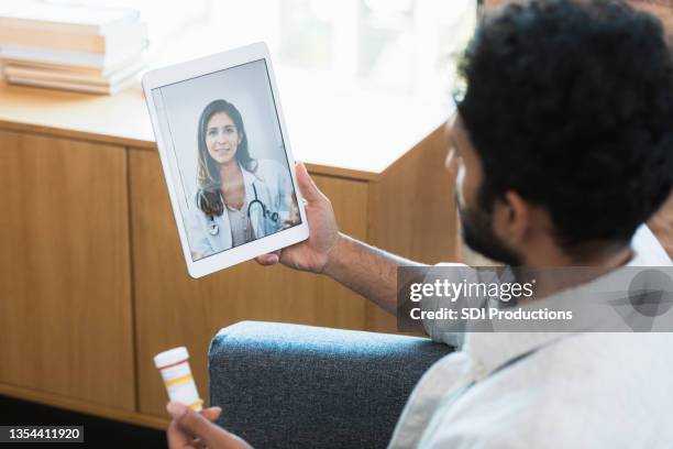 mann spricht mit arzt über telemedizin-termin - mann tabletten stock-fotos und bilder