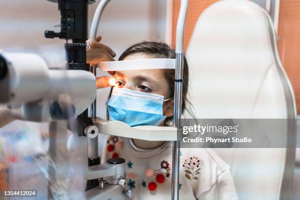 ophthalmologist is checking the eye vision of cute child in modern clinic - eye exam stock pictures, royalty-free photos & images