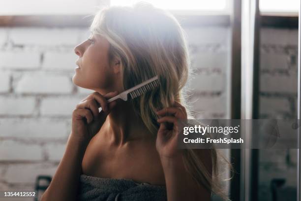 porträt einer schönen kaukasischen frau, die nach dem duschen ihre langen blonden haare kämmt - haarpflege stock-fotos und bilder