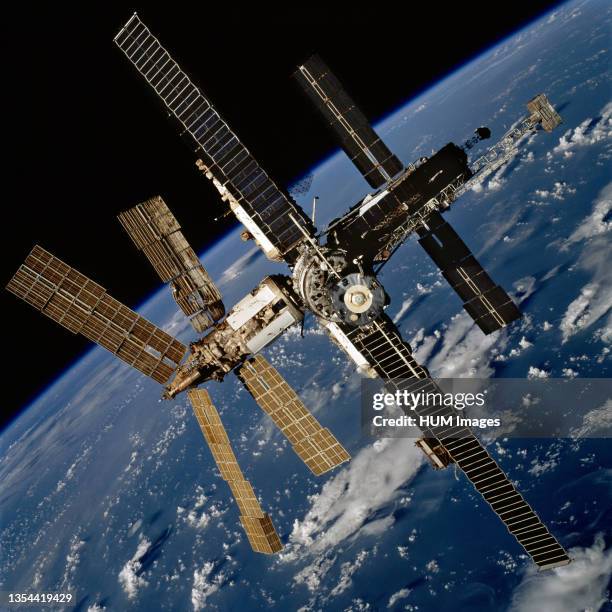 70mm view of Russia?s Mir Space Station backdropped against a cloud-covered Earth was photographed during a fly-around by the Space Shuttle Atlantis...