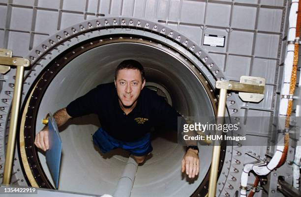 Astronaut Michael A. Baker, mission commander, floats through the tunnel leading from the Space Shuttle Atlantis mid-deck into Spacehab Double Module...