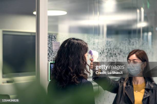 employees going through temperature checks in office - misurare la temperatura foto e immagini stock