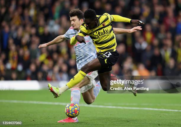 Ismaila Sarr of Watford FC shoots under pressure from Harry Maguire of Manchester United during the Premier League match between Watford and...