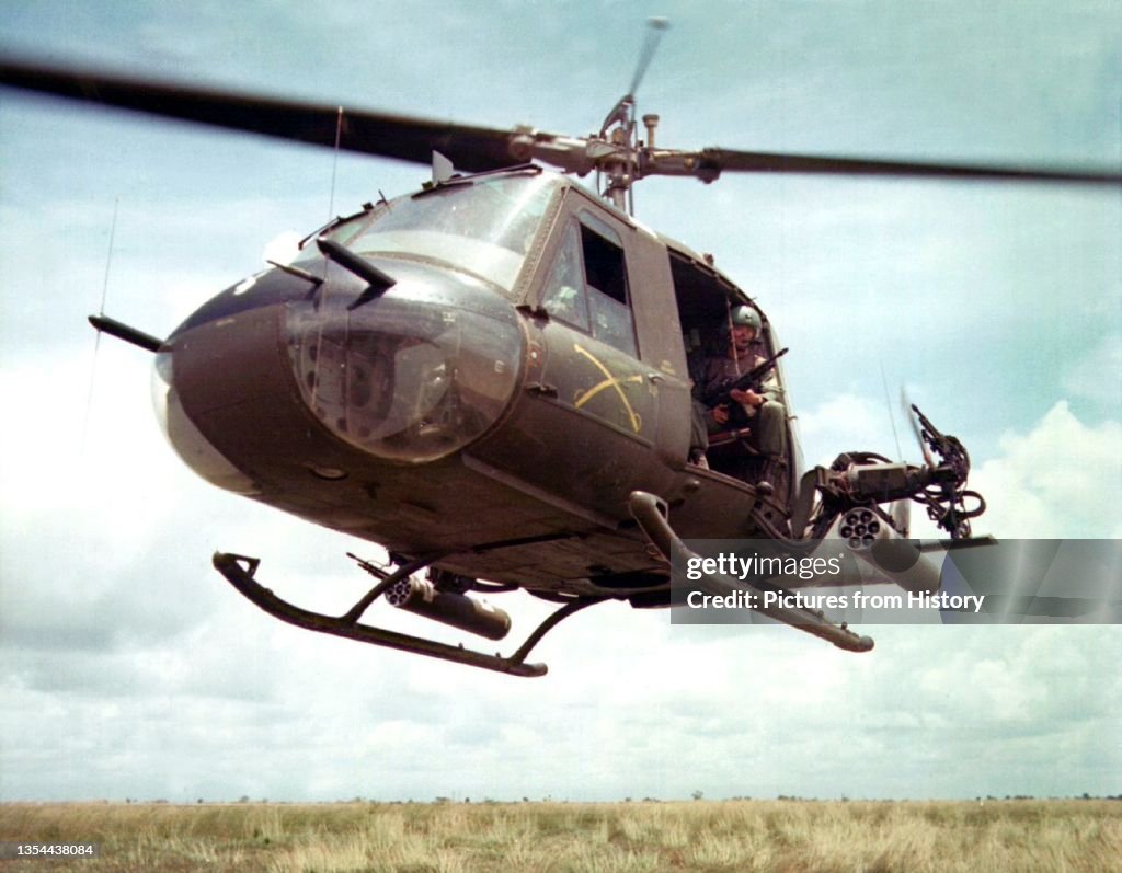 Vietnam: U.S. Army Sgt. Dennis Troxel sits as 'Shotgun Rider' in the door of a Bell UH-1B Huey helicopter of the 179th Aviation Company, Vietnam, 1965
