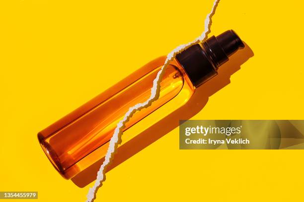 orange  bottle of organic  moisturizing essential oil for body or hair on yellow color background with torn paper effect. routine step for healthy skin care. - oily skin stock pictures, royalty-free photos & images