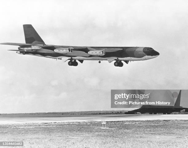 Stratofortress aircraft waits beside the runway as a B-52G approaches for landing after completing a bombing mission over North Vietnam during...