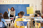 Teacher and Schoolgirl Exchanging High-Five in Classroom