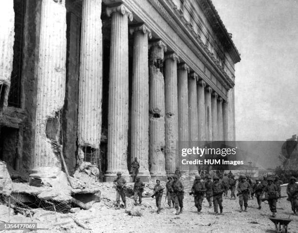 Company F, 145th Infantry, 37th Infantry Division Soldiers move past the General Post Office building on their way to assault the walled city of...