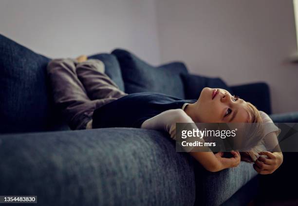 a boy laying on the sofa upside down - child alone stockfoto's en -beelden