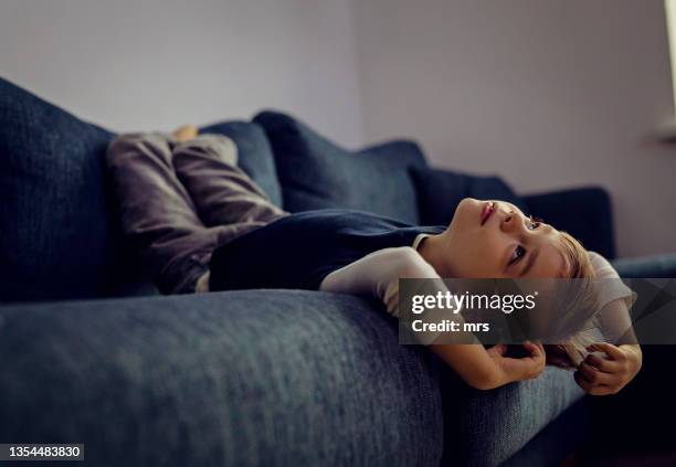 a boy laying on the sofa upside down - watching tv at home stock pictures, royalty-free photos & images