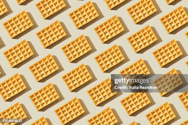 repeated belgian waffles on the beige background - waffle stock-fotos und bilder