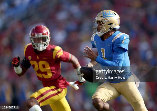 Dorian Thompson-Robinson of the UCLA Bruins scrambles from the tackle of Xavion Alford of the USC Trojans during the first quarter at Los Angeles...