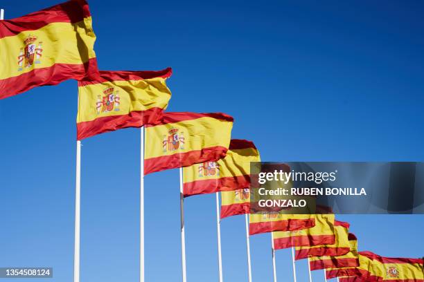 many spanish flag waving in the wind in a row against blue sky. - spanish flag stock pictures, royalty-free photos & images