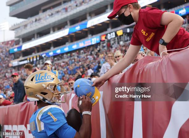 Dorian Thompson-Robinson of the UCLA Bruins celebrates his touchdown run, to take a 28-10 lead over the USC Trojans, by signing an autograph,...