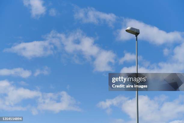 low angle view of rectangular shape metallic street light against blue sky with many white clouds - turn off light stock pictures, royalty-free photos & images