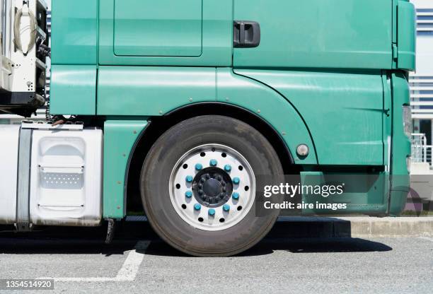 close-up of side view of big green truck with big tires is parked on the road on a sunny day - old truck stock-fotos und bilder