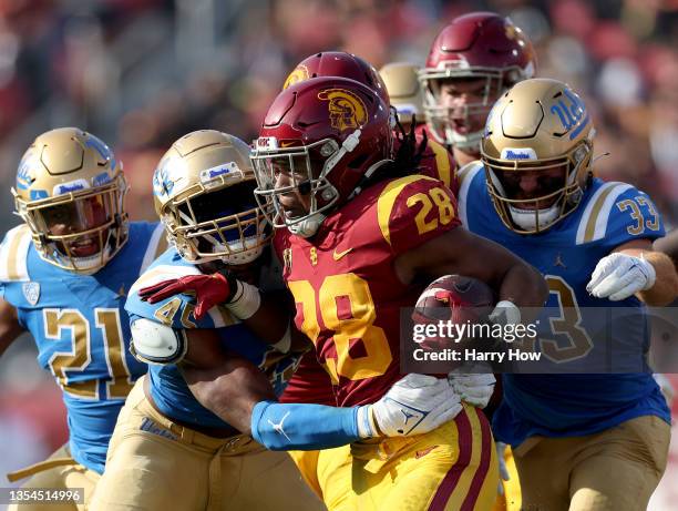 Keaontay Ingram of the USC Trojans rushes the ball as he is met by Mitchell Agude of the UCLA Bruins during the first quarter at Los Angeles Memorial...