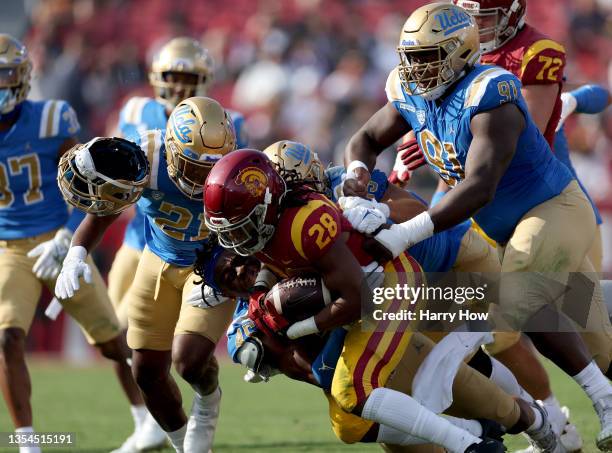 Keaontay Ingram of the USC Trojans rushes as he is tackled by Mitchell Agude of the UCLA Bruins, losing his helmet, during the first quarter at Los...