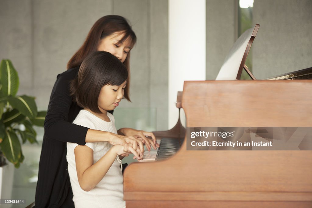 Mother teaching  daughter,  playing piano