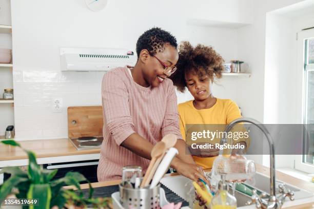 african american girl helping her grandma washing dishes - washing dishes bildbanksfoton och bilder